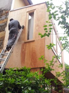 peintre sur une échelle contre un bardage en bois