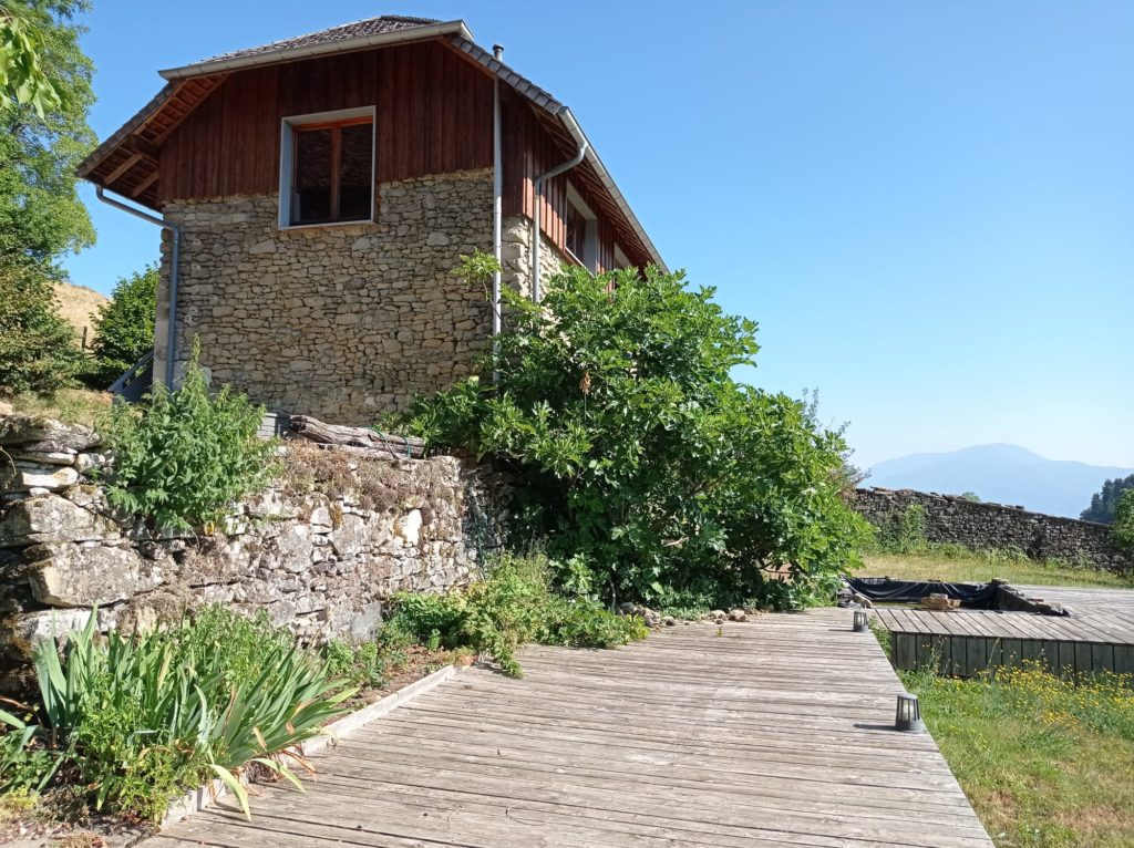 Terrasse en bois douglas grisée sous une grange en pierres